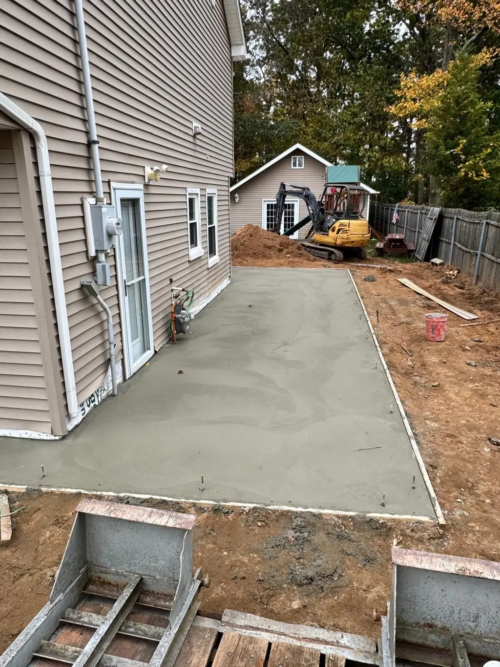 Concrete slab poured and finished alongside an existing home